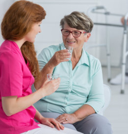 a nurse and an elderly woman drinking water.