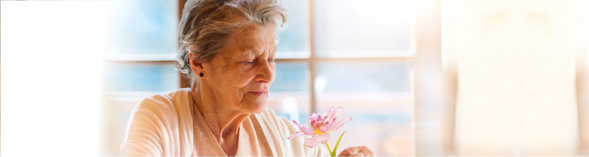 an elderly woman smelling a flower